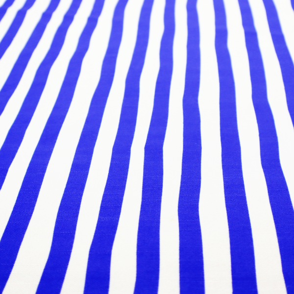 A white fabric patterned with vertical, hand-drawn blue stripes that feature a slight, organic waviness.   