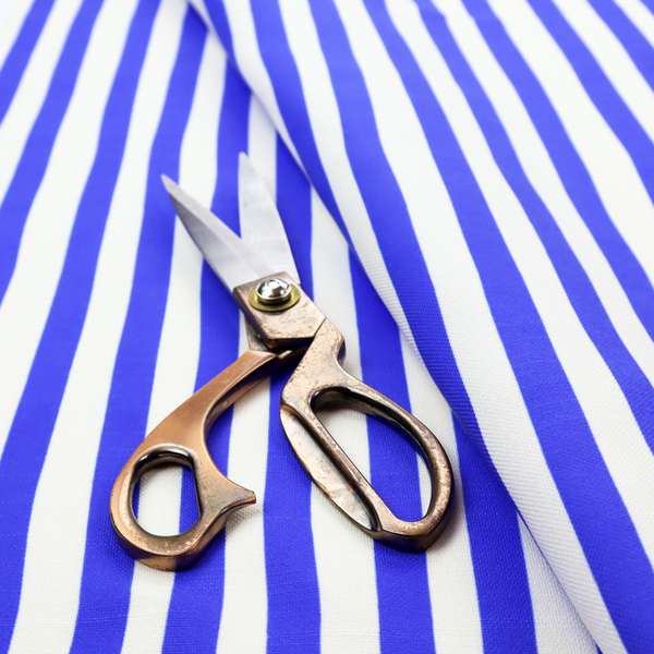 A white fabric patterned with vertical, hand-drawn blue stripes that feature a slight, organic waviness.   