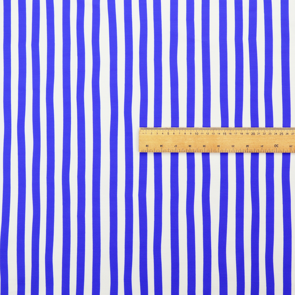 A white fabric patterned with vertical, hand-drawn blue stripes that feature a slight, organic waviness.   