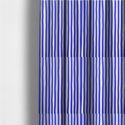The fabric used to create these made-to-measure curtains is a white fabric patterned with vertical, hand-drawn blue stripes that feature a slight, organic waviness.   
