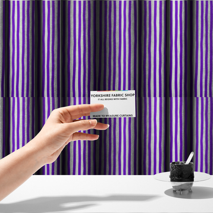 The fabric used to create these made-to-measure curtains is a white fabric patterned with vertical, hand-drawn purple stripes that feature a slight, organic waviness.