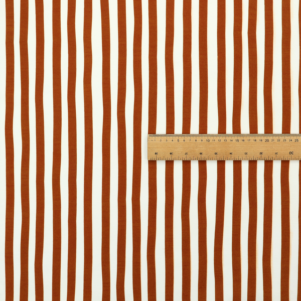 A white fabric patterned with vertical, hand-drawn brown stripes that feature a slight, organic waviness.