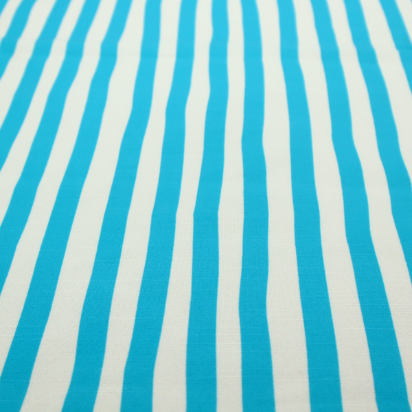 A white fabric patterned with vertical, hand-drawn light blue stripes that feature a slight, organic waviness.
