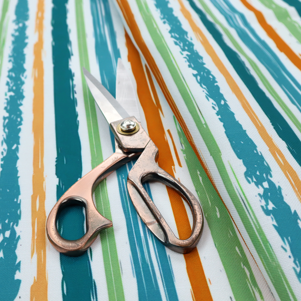A white fabric patterned with multi-coloured vertical, hand-drawn stripes in teal, green, blue, and orange with a slight, organic waviness.