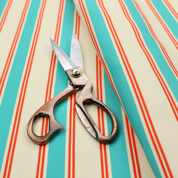 A white fabric patterned with vertical, hand-drawn turquoise and red double stripes that feature a slight, organic waviness.