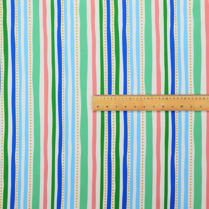 A white fabric patterned with vertical, hand-drawn multi-coloured stripes in green, blue, pink, and light blue alongside dotted lines that feature an organic waviness.