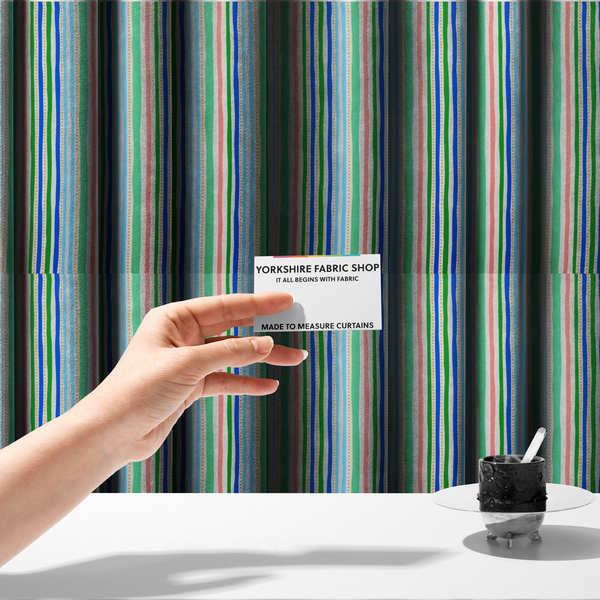 The fabric used to create these made-to-measure curtains is a white fabric patterned with vertical, hand-drawn multi-coloured stripes in green, blue, pink, and light blue alongside dotted lines that feature an organic waviness.