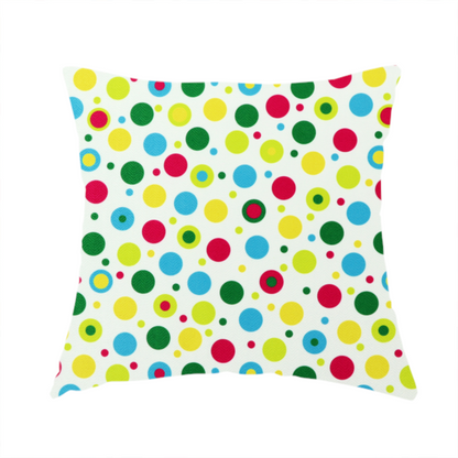 The fabric used to create this handmade cushion is a playful fabric pattern featuring scattered polka dots and concentric circles in various sizes and colours, including pink, blue, green, yellow, and lime on a white background.