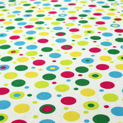A playful fabric pattern featuring scattered polka dots and concentric circles in various sizes and colours, including pink, blue, green, yellow, and lime on a white background.