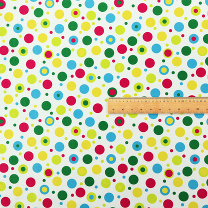 A playful fabric pattern featuring scattered polka dots and concentric circles in various sizes and colours, including pink, blue, green, yellow, and lime on a white background.