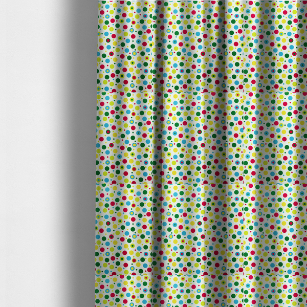 The fabric used to create these made-to-measure curtains is a playful fabric pattern featuring scattered polka dots and concentric circles in various sizes and colours, including pink, blue, green, yellow, and lime on a white background.