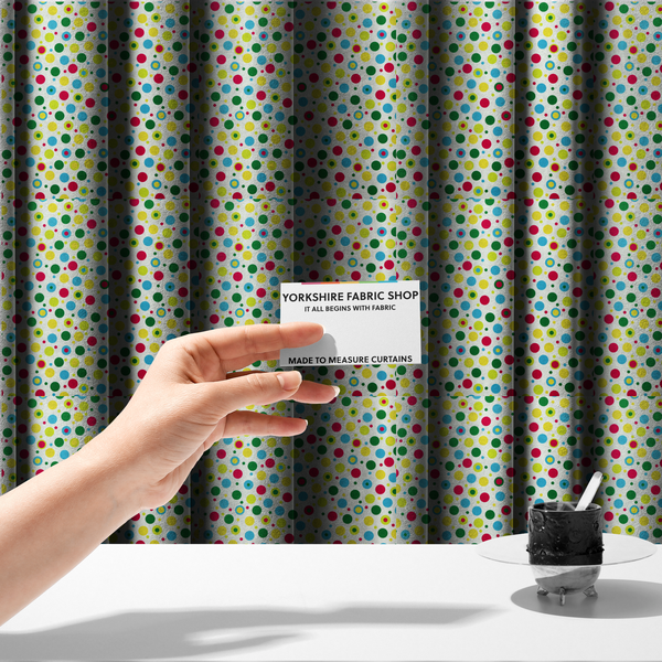 The fabric used to create these made-to-measure curtains is a playful fabric pattern featuring scattered polka dots and concentric circles in various sizes and colours, including pink, blue, green, yellow, and lime on a white background.
