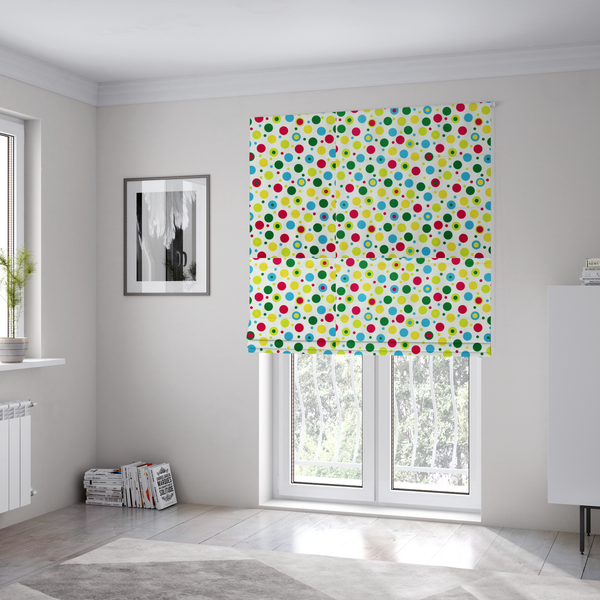 The fabric used to create these Roman blinds is a playful fabric pattern featuring scattered polka dots and concentric circles in various sizes and colours, including pink, blue, green, yellow, and lime on a white background.