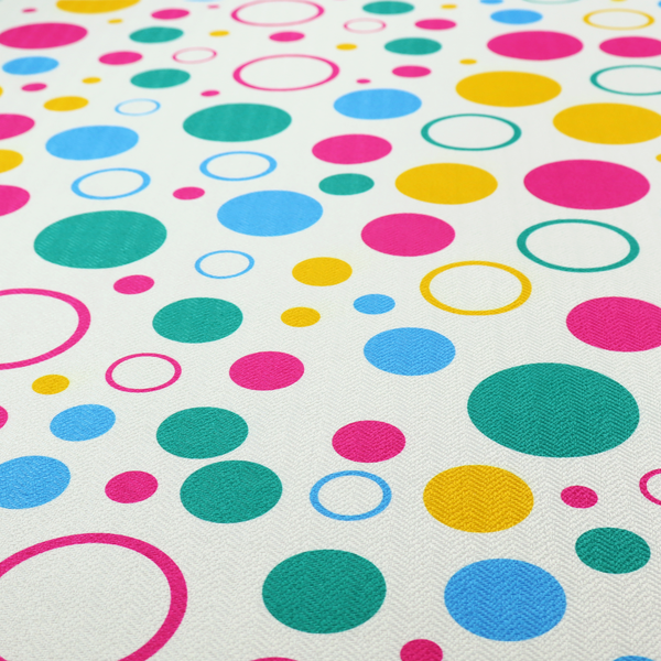 A fun and colourful fabric pattern featuring random solid and hollow polka dots in pink, teal, yellow, and blue on a white background.