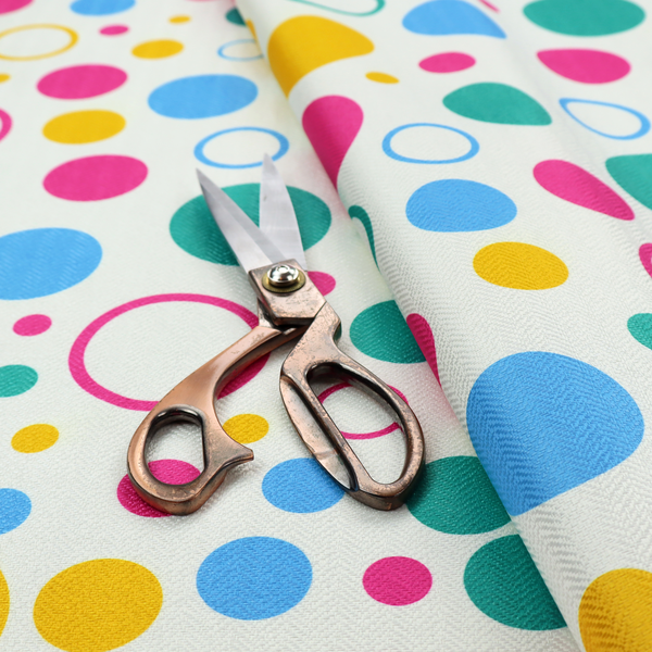 A fun and colourful fabric pattern featuring random solid and hollow polka dots in pink, teal, yellow, and blue on a white background.