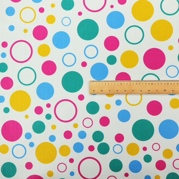 A fun and colourful fabric pattern featuring random solid and hollow polka dots in pink, teal, yellow, and blue on a white background.