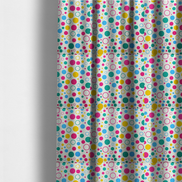 The fabric used to create these made-to-measure curtains is a fun and colourful fabric pattern featuring random solid and hollow polka dots in pink, teal, yellow, and blue on a white background.