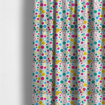 The fabric used to create these made-to-measure curtains is a fun and colourful fabric pattern featuring random solid and hollow polka dots in pink, teal, yellow, and blue on a white background.