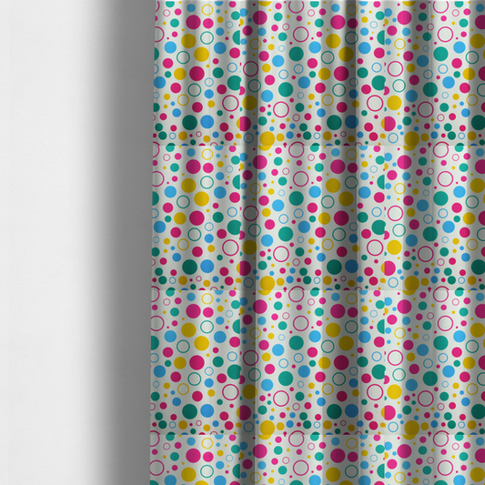 The fabric used to create these made-to-measure curtains is a fun and colourful fabric pattern featuring random solid and hollow polka dots in pink, teal, yellow, and blue on a white background.