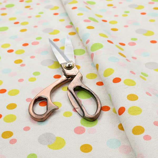 A subtle fabric pattern featuring scattered pastel and bright polka dots in shades of yellow, orange, light green, grey, and soft blue on a white background.