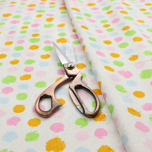 A whimsical fabric pattern featuring scattered painterly dots in soft shades of pink, yellow, lime green, and light blue on a white background.