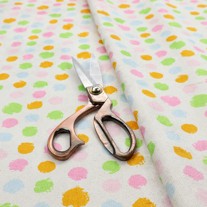 A whimsical fabric pattern featuring scattered painterly dots in soft shades of pink, yellow, lime green, and light blue on a white background.