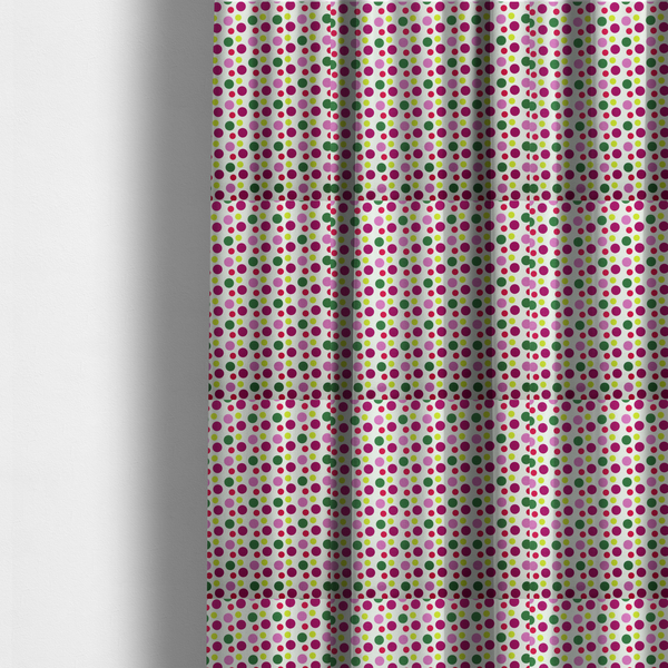 The fabric used to create these made-to-measure curtains is a  playful fabric pattern featuring neat vertical rows of alternating polka dots in shades of magenta, pink, green, and lime on a white background.