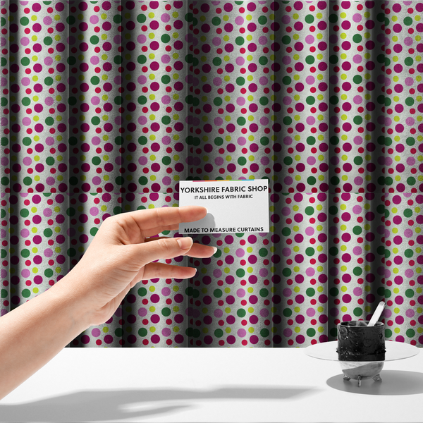 The fabric used to create these made-to-measure curtains is a  playful fabric pattern featuring neat vertical rows of alternating polka dots in shades of magenta, pink, green, and lime on a white background.