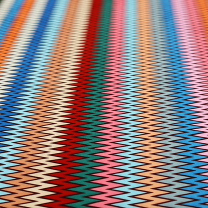 A vibrant fabric pattern featuring tight vertical rows of colourful zigzag lines in shades of orange, pink, blue, red, green, and beige.