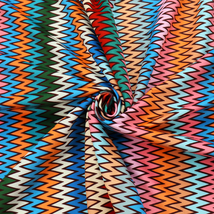 A vibrant fabric pattern featuring tight vertical rows of colourful zigzag lines in shades of orange, pink, blue, red, green, and beige.