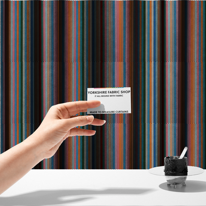The fabric used to create these made-to-measure curtains is a vibrant fabric pattern featuring tight vertical rows of colourful zigzag lines in shades of orange, pink, blue, red, green, and beige.