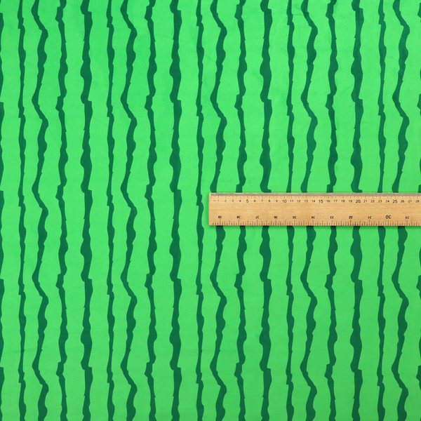 A playful fabric pattern featuring vertical wavy dark green stripes running across a bright green background.