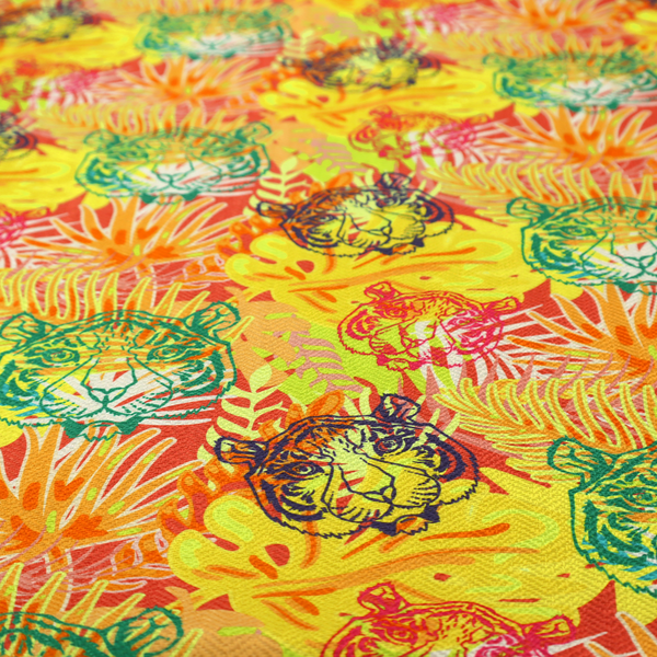 The image features a vibrant, repeating tropical pattern set against a bright yellow and orange background. The design is filled with stylized jungle foliage, including overlapping palm fronds and leaves. Interspersed throughout the pattern are illustrative tiger faces rendered in different colours, including striking shades of green, dark blue, and pinkish-red.   