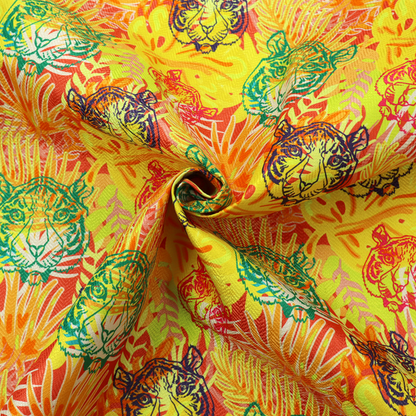 The image features a vibrant, repeating tropical pattern set against a bright yellow and orange background. The design is filled with stylized jungle foliage, including overlapping palm fronds and leaves. Interspersed throughout the pattern are illustrative tiger faces rendered in different colours, including striking shades of green, dark blue, and pinkish-red.   