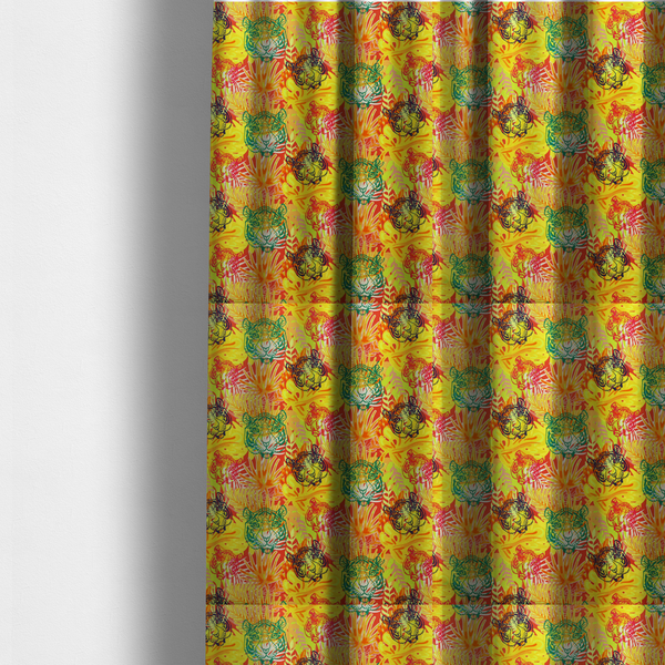 The fabric used to create these made-to-measure curtains features a vibrant, repeating tropical pattern set against a bright yellow and orange background. The design is filled with stylized jungle foliage, including overlapping palm fronds and leaves. Interspersed throughout the pattern are illustrative tiger faces rendered in different colours, including striking shades of green, dark blue, and pinkish-red.   