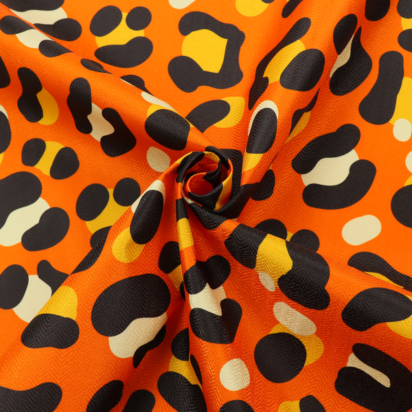 The image features a bold leopard print upholstery fabric in a vibrant orange background with black spots featuring yellow and cream highlights.   