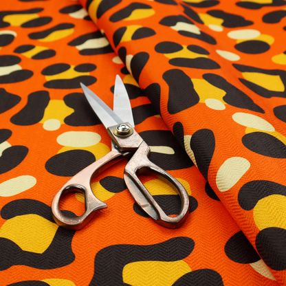 The image features a bold leopard print upholstery fabric in a vibrant orange background with black spots featuring yellow and cream highlights.   