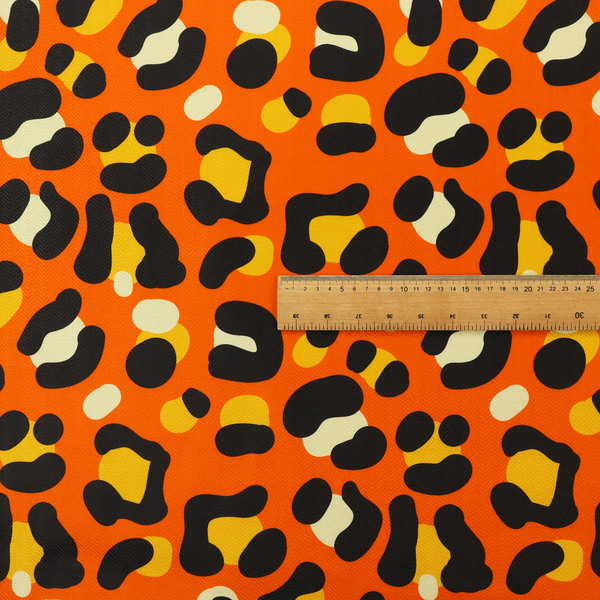 The image features a bold leopard print upholstery fabric in a vibrant orange background with black spots featuring yellow and cream highlights.   