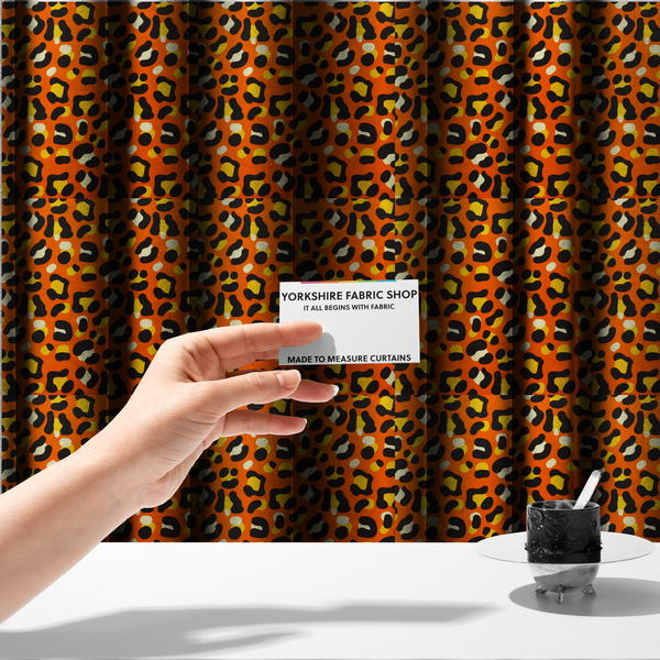 The fabric used to create these made-to-measure curtains features a bold leopard print upholstery fabric in a vibrant orange background with black spots featuring yellow and cream highlights.   