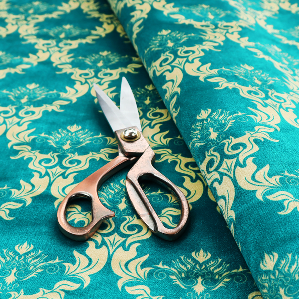 The image features an intricate, repeating damask pattern in a light cream colour set against a textured teal background.   