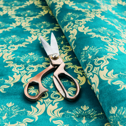The image features an intricate, repeating damask pattern in a light cream colour set against a textured teal background.   
