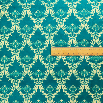 The image features an intricate, repeating damask pattern in a light cream colour set against a textured teal background.   