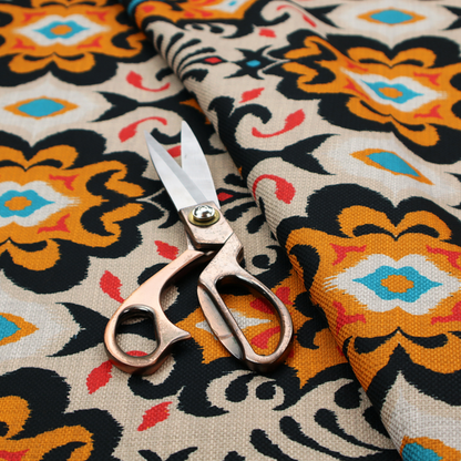 The image features a vibrant, symmetrical ikat-style pattern set against a light background. The design includes elaborate floral motifs and geometric shapes in striking shades of black, orange, yellow, bright red, and turquoise.   
