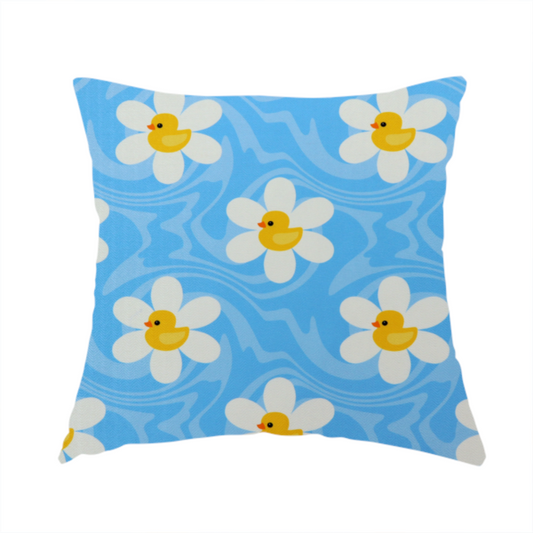 The fabric used to create this handmade cushion features a repeating pattern of white daisies with yellow centres shaped like little rubber ducks, all set against a wavy blue background.   