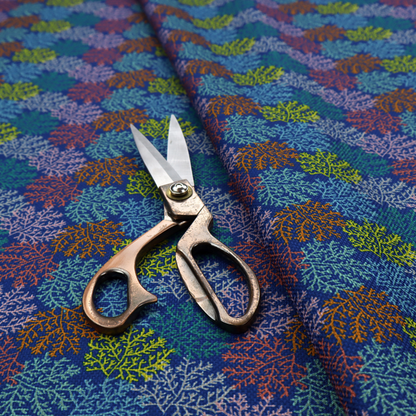 The image features an intricate, dense repeating pattern of sea coral or moss-like clusters set against a deep blue background. The design is filled with detailed organic shapes rendered in various vibrant colours, including lime green, rust orange, teal, and soft pink.