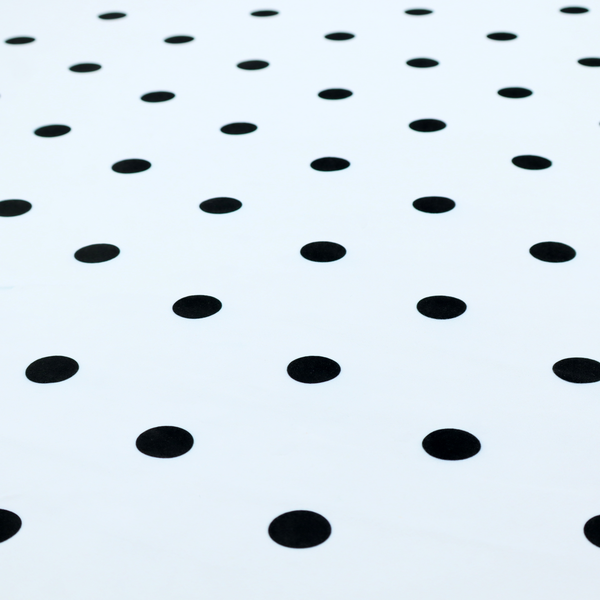 A white fabric pattern featuring evenly spaced black polka dots arranged in horizontal and vertical rows.