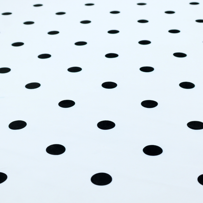A white fabric pattern featuring evenly spaced black polka dots arranged in horizontal and vertical rows.