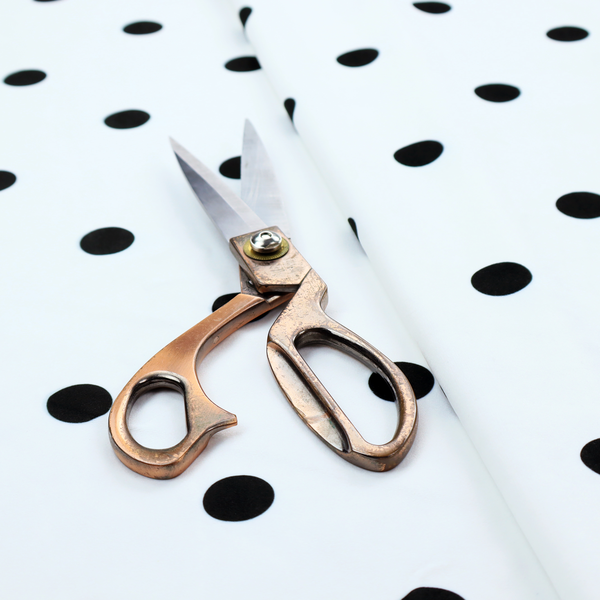 A white fabric pattern featuring evenly spaced black polka dots arranged in horizontal and vertical rows.