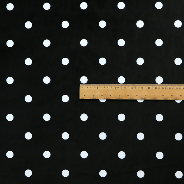 A black fabric pattern featuring evenly spaced white polka dots arranged in horizontal and vertical rows.