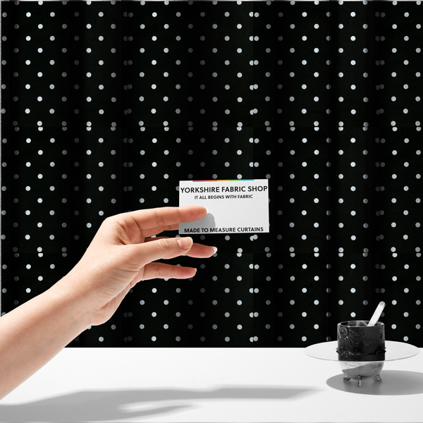 The fabric used to create these made-to-measure curtains is a black fabric pattern featuring evenly spaced white polka dots arranged in horizontal and vertical rows.
